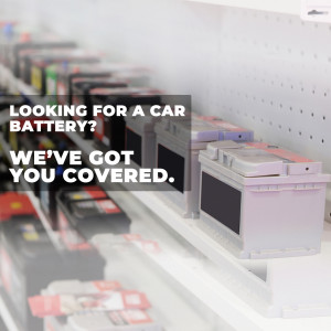 A store shelf filled with car batteries with a promotional sign.