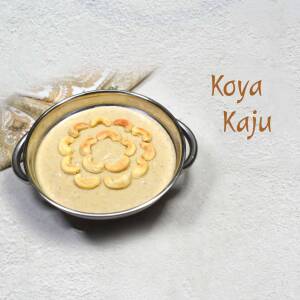 A silver bowl filled with Koya Kaju, a traditional Indian sweet, decorated with cashew nuts.