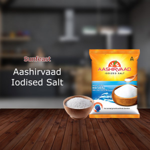 Aashirvaad Iodized Salt packaging with a bowl of salt and a wooden surface.