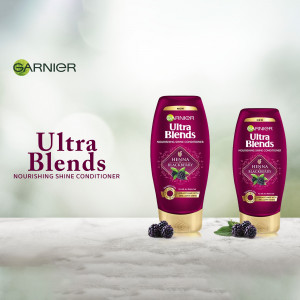 Two bottles of Garnier Ultra Blends Henna & Blackberry Nourishing Shine Conditioner with blackberries and henna leaves.