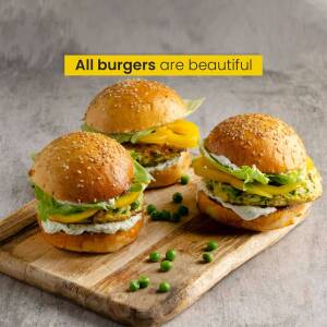 Close-up of three veggie burgers on a wooden board with peas.