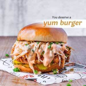 Close-up of a delicious, crispy chicken burger with sauce and pickles.