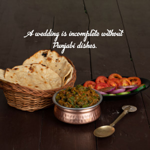 A rustic still life of Punjabi dishes, including roti, saag, and a tomato onion salad, with the text 'A wedding is incomplete without Punjabi dishes.'
