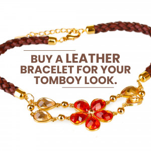 Close-up of a brown leather bracelet with a gold and red floral charm.