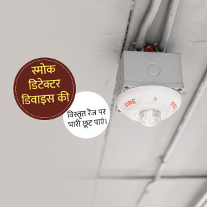 Close-up of a smoke detector and fire alarm installed on a ceiling with a warning sign in Hindi.