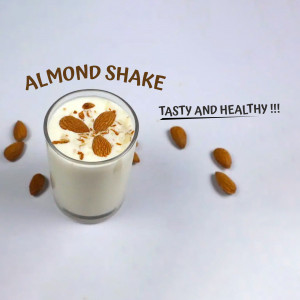 Glass of almond shake with almonds around it