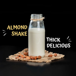 A glass bottle of almond shake with almonds around it