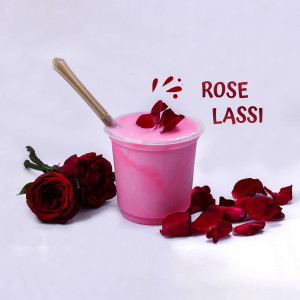 A refreshing glass of pink Rose Lassi with rose petals and roses