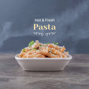 A close-up of a white bowl filled with penne pasta covered in a creamy tomato sauce and grated cheese, garnished with fresh herbs.