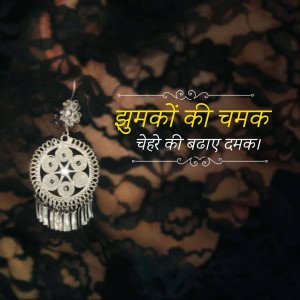 Silver earrings with intricate design on a black lace background