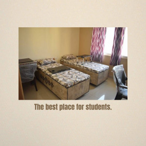 Two single beds in a student dormitory room with study tables and curtains.