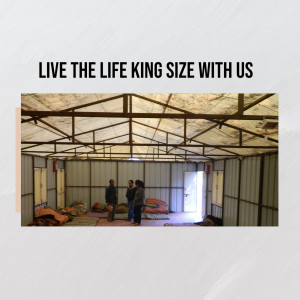 Interior view of a temporary shelter housing refugees with people standing inside.