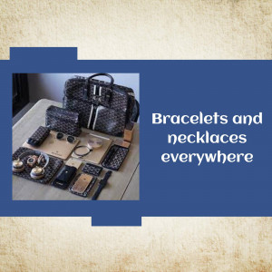 A collection of designer bracelets, necklaces, wallets, and a handbag displayed on a table.