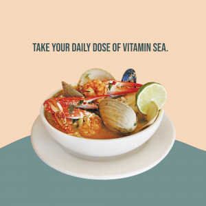 A bowl of colorful seafood in a creamy broth with the text 'Take Your Daily Dose of Vitamin Sea.'