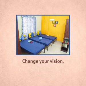 A dormitory room with three single beds, blue bedding, and yellow walls.