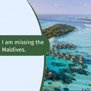 Aerial view of a tropical island in the Maldives with overwater bungalows and turquoise water.