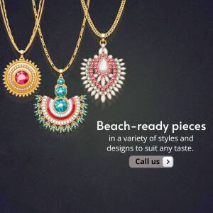 Close-up of three ornate gold necklaces with gemstone pendants on a dark background.