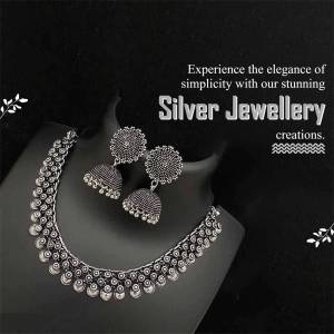 Close-up of a silver necklace and earring set on a black background