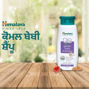 Himalaya Gentle Baby Shampoo bottle on a wooden surface with flowers and nuts.
