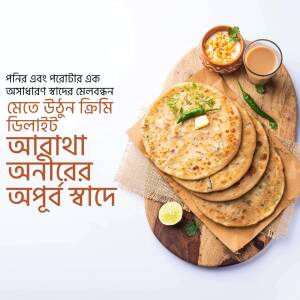 A wooden board with stacked parathas, a bowl of lentils, a glass of tea, and condiments.
