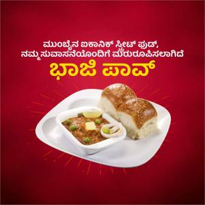 A plate of Pav Bhaji with two Pav buns and a bowl of spicy curry.