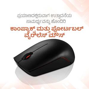 Black wireless computer mouse on a white surface with Kannada text in the background.