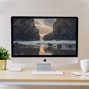 Computer displaying a scenic coastal landscape with rocks and ocean.