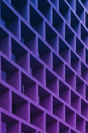 Close-up of a modern building facade with a repeating geometric pattern in shades of purple and blue.