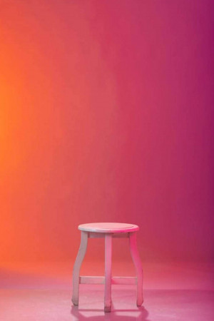 White stool against a vibrant pink and orange gradient background