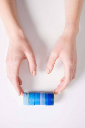 Hands holding a stack of blue colored paper strips