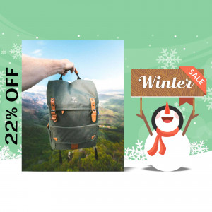 A gray backpack held against a mountain landscape with a winter sale promotion.