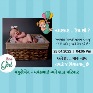 Newborn baby girl in a basket with Gujarati text announcing her birth.
