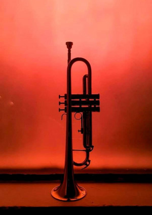 A silhouette of a trumpet against a red background
