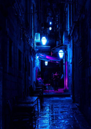 Narrow alleyway illuminated with blue and purple lights in Dubrovnik, Croatia.