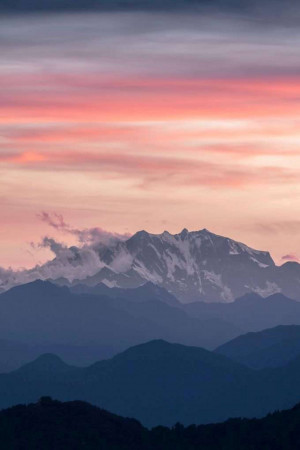 Snow-capped mountains silhouetted against a vibrant pink and purple sunset