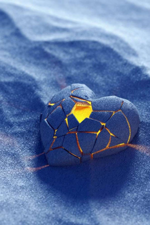 A cracked, dark heart-shaped object partially buried in blue sand with glowing orange cracks.