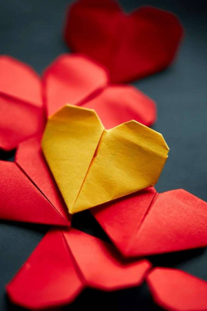 Close-up of red and yellow origami hearts arranged like a flower