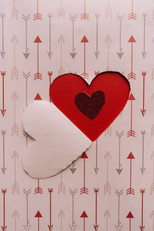 A red heart with a glittery center on a white background with red arrow patterns.