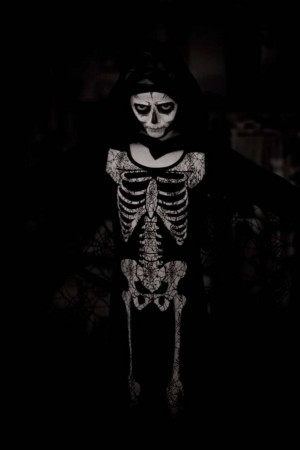 A person with a Dia de los Muertos (Day of the Dead) skull makeup, wearing a skeleton-themed outfit.