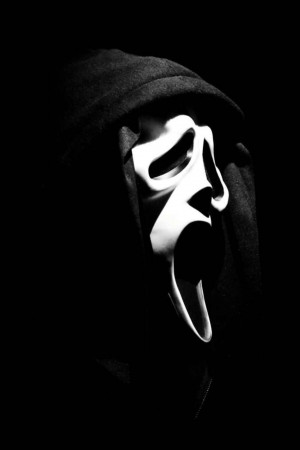 Close-up of a person wearing a Scream mask in a hooded sweatshirt.