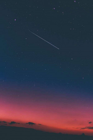A dark night sky with a shooting star and a pink horizon.