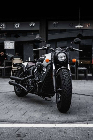 Front view of a black Indian motorcycle parked on a city street in front of a cafe.