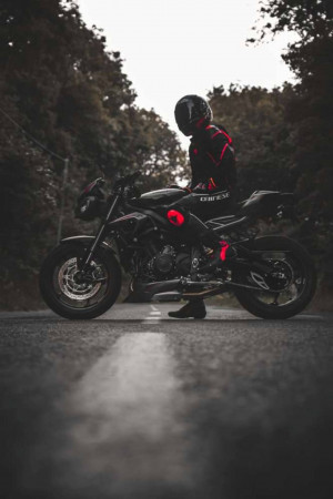 A motorcycle and rider standing on a road.