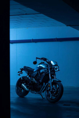 A silver and black motorcycle parked in a dimly lit, blue-toned parking garage.