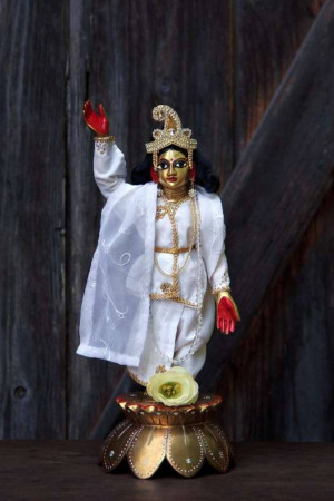 A beautifully dressed idol of Lord Krishna with a raised hand