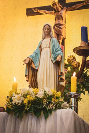 Statues of Mary and Jesus Christ with candles and flowers in a church setting