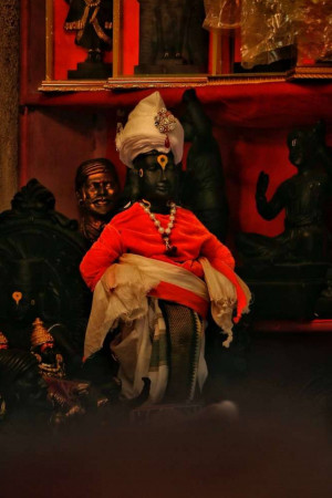 Close-up of a deity statue dressed in red and white, with other statues in the background.