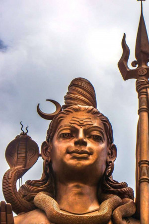 Close-up of a large bronze statue of Lord Shiva with a trident and snake