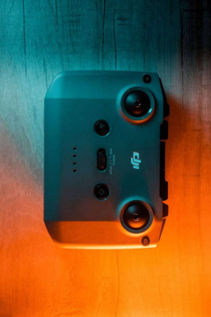 Overhead shot of a gray DJI Mini 3 Pro drone controller on a colorful gradient background.