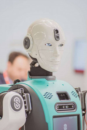 Close-up of a white and teal humanoid robot with a human-like face.